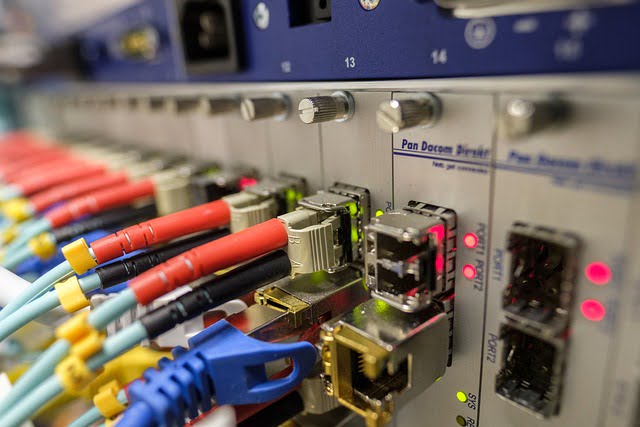 A router with lots of fibre optic and ethernet cables plugged in.