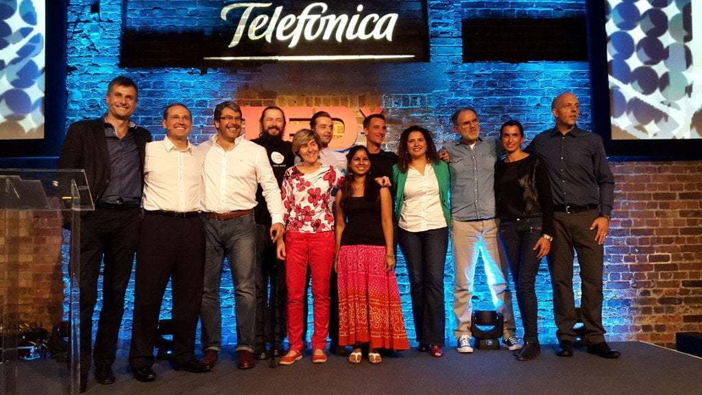 A group of smiling presenters stand on stage