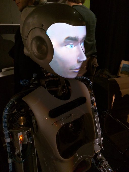 A robot with a backlit human face.