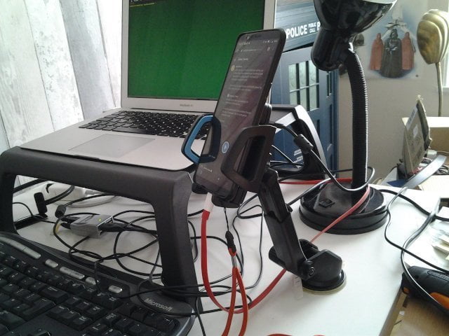 A phone holder for a car, but it is stuck to a desk.