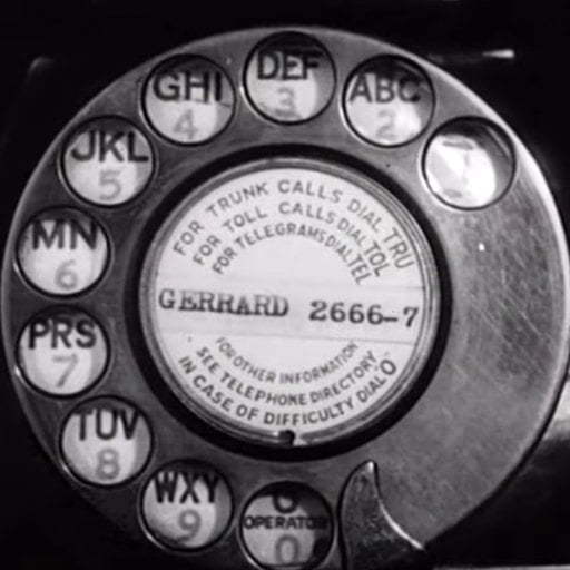 A black and white photo of an old rotary dial phone.
