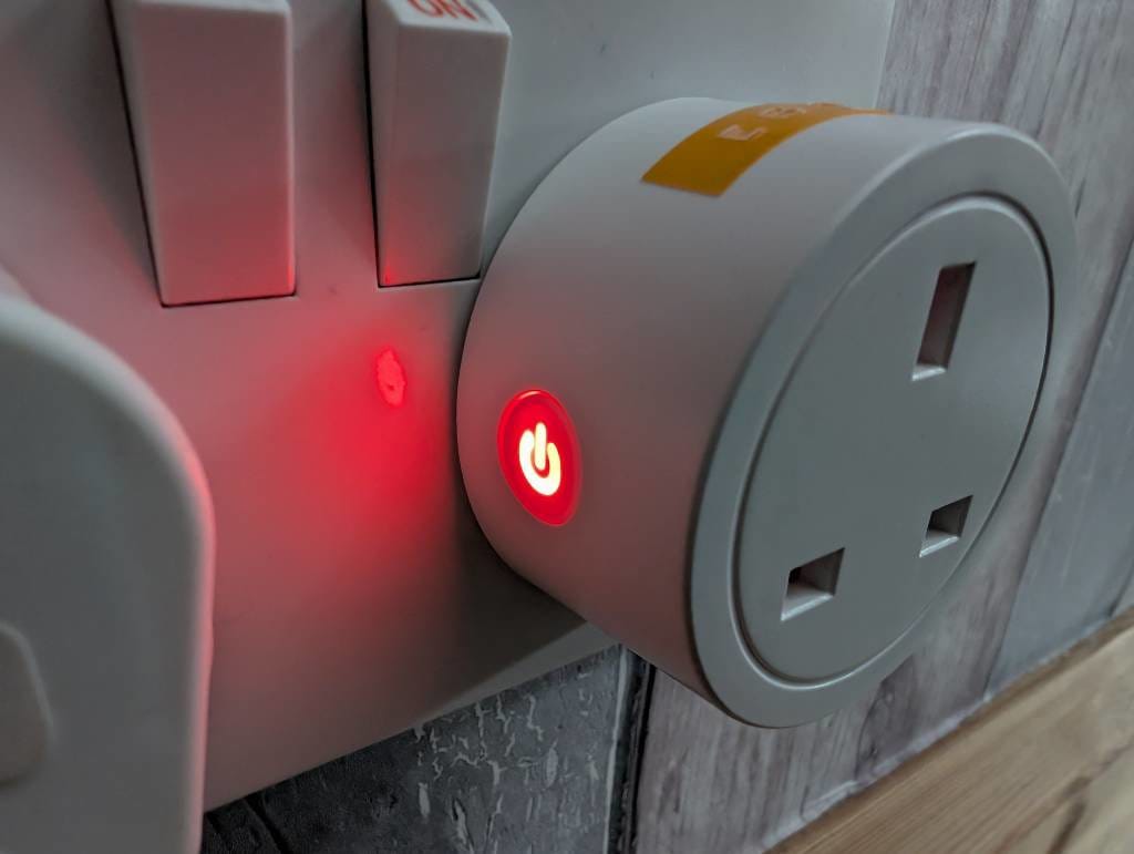 A small smartplug with a glowing red power symbol.